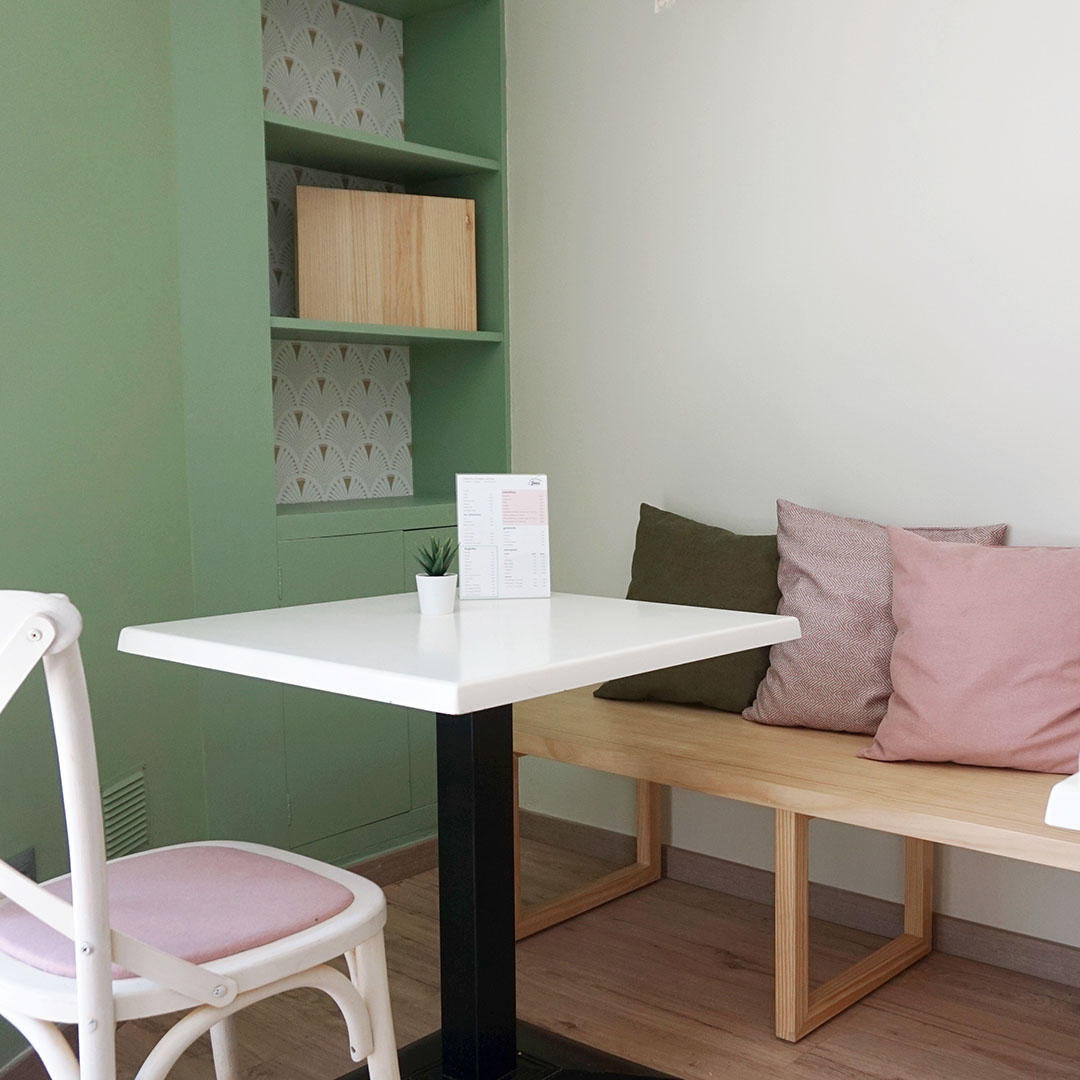 raco de cafeteria amb banc de fusta i coixins verd i rosa