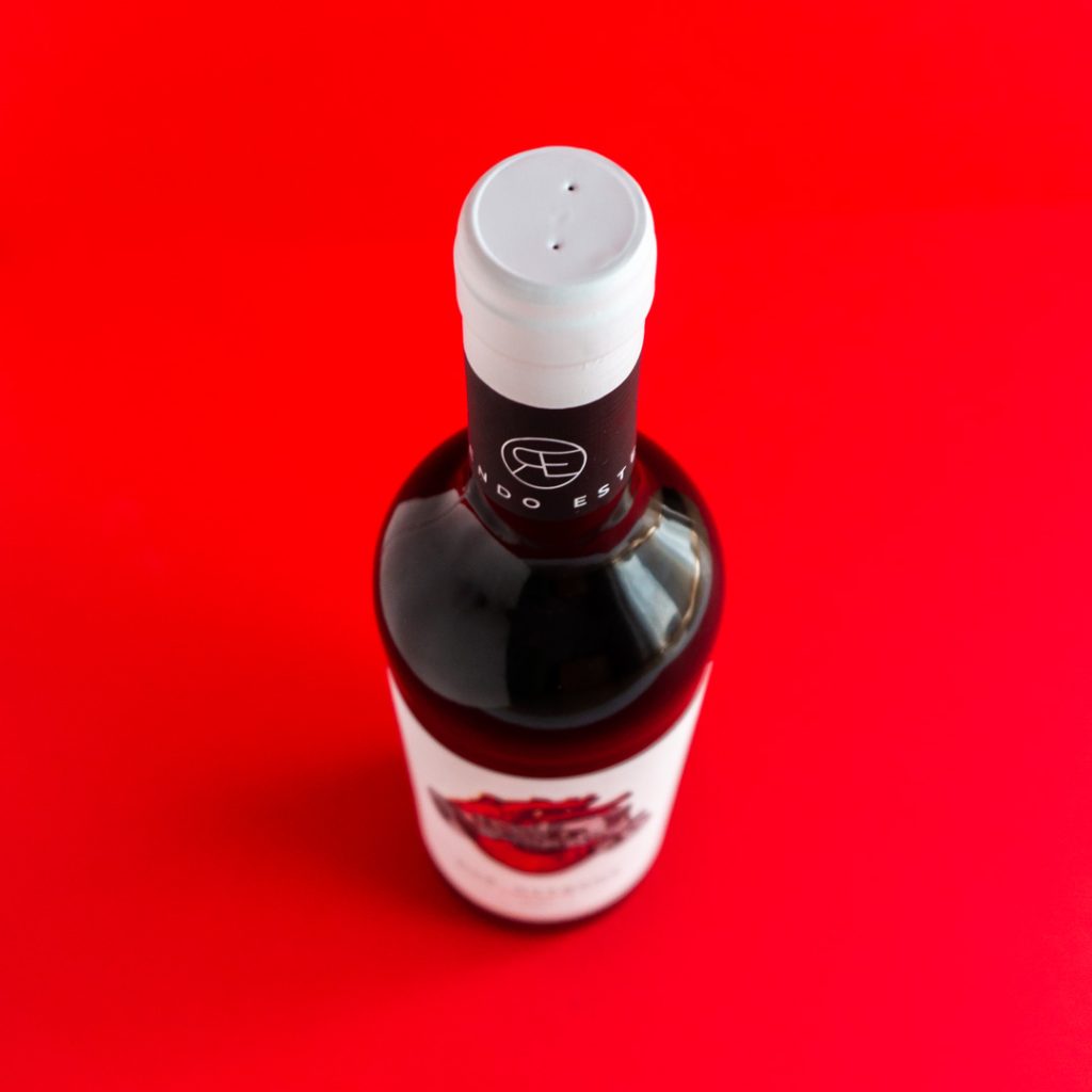 vista superior d'una ampolla de vi Dos Germans sobre un fons roig