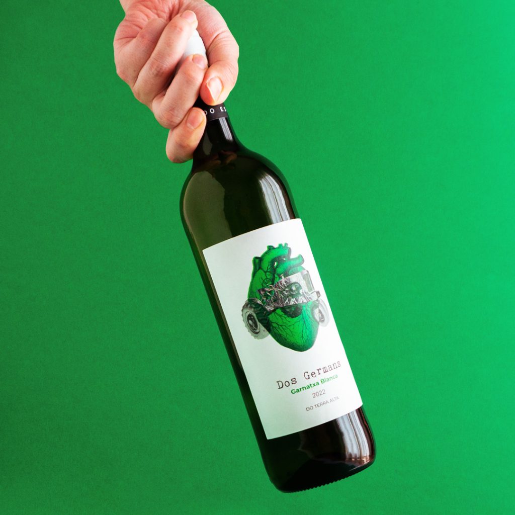 Ampolla de vi blanc agafada d'una mà sobre fons verd