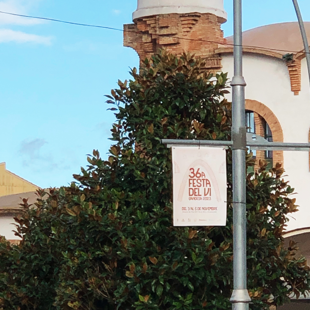 Banderola del cartell de la Festa del Vi amb la cooperativa de Gandesa i un arbre al fons