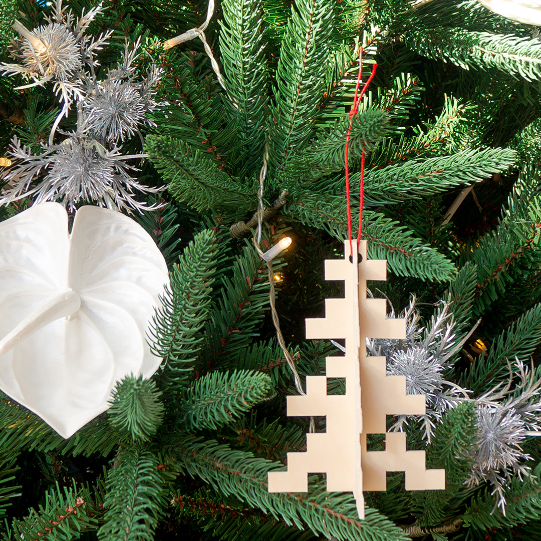 Ornament de nadal en forma de arbre penjat a un arbre de Nadal amb decoracions de color blanc i platejades