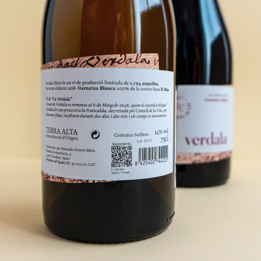 Part posterior de l'etiqueta de l'ampolla de vi Verdala amb una ampolla de vi negre al fons