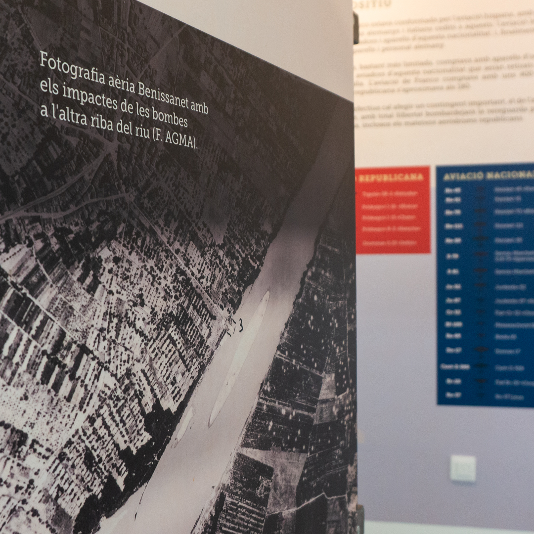 Detall d'una fotografia antiga amb un peu de foto i un mural al fons