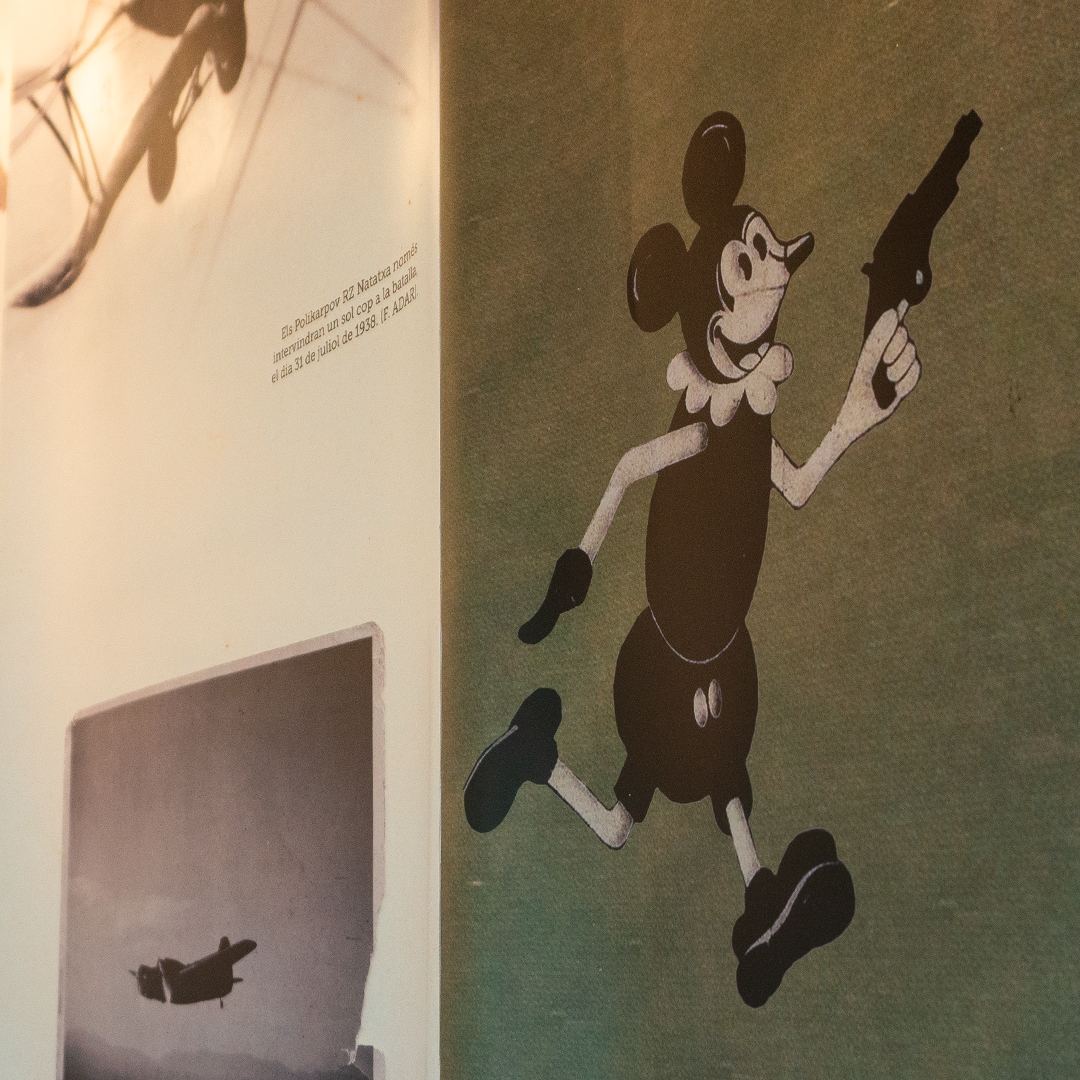 Detall d'un Mickey Mouse amb una pistola sobre un fons verd