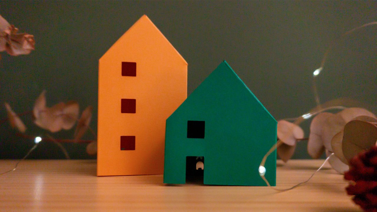 Cases de papiroflèxia sobre una fusta i fons verd amb llums i plantes al voltant