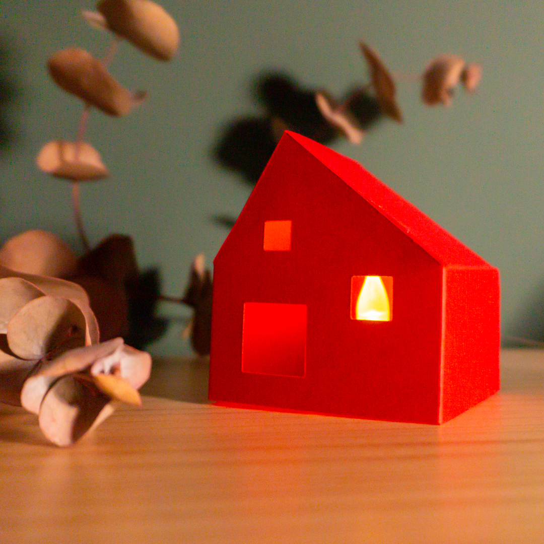 Cases de papiroflèxia sobre una fusta i fons verd amb llums i plantes al voltant