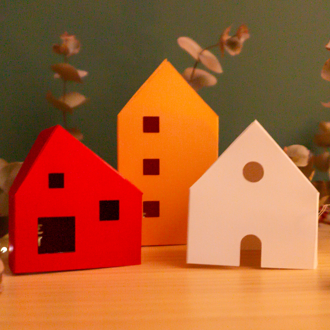 Cases de papiroflèxia sobre una fusta i fons verd amb llums i plantes al voltant