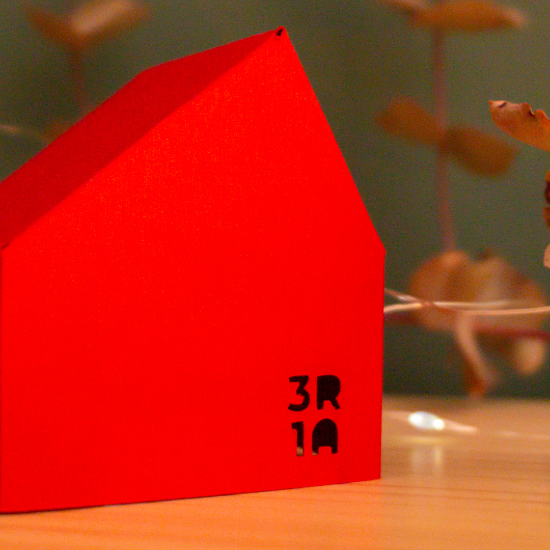 Cases de papiroflèxia sobre una fusta i fons verd amb llums i plantes al voltant