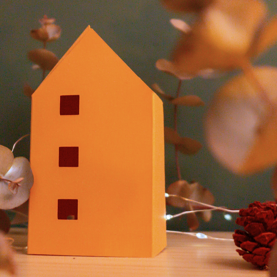 Cases de papiroflèxia sobre una fusta i fons verd amb llums i plantes al voltant